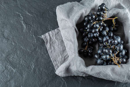 Dark fresh grape in basket on a gray tableclothの写真素材