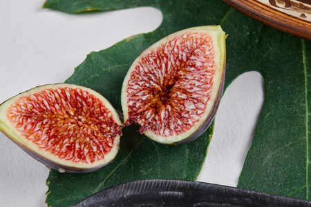Sliced black fig on white background with a leaf