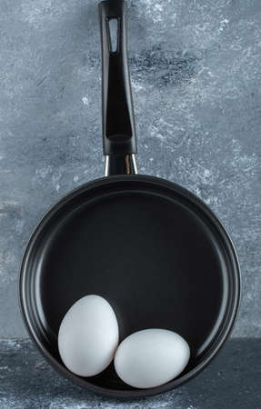 Vertical photo of two chicken egg and black frying panの写真素材