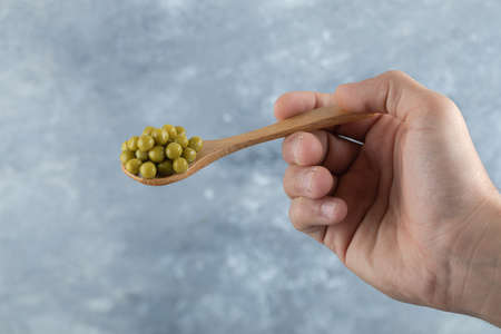 Man holding spoon olive with hand over grey background