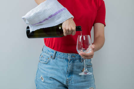 Young girl in red shirt holding a bottle of wine and a glass