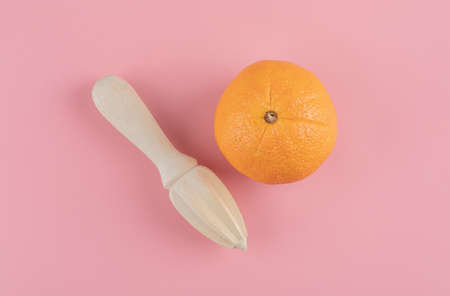 Orange and wooden reamer on pink backgroundの写真素材
