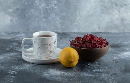 Cup of tea, lemon and bowl of dried flowers on marble backgroundの写真素材