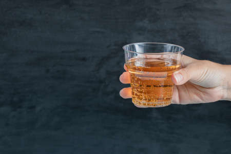 Holding a plastic cup of yellow drinkの写真素材