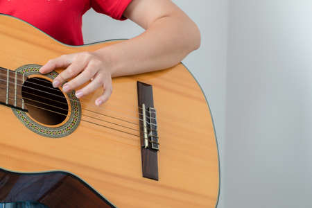Female model in red shirt holding a wooden guitar