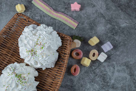 White meringue cookies in a wooden platter with jellybeans around