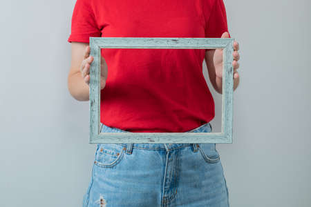 Young girl in red shirt holding a metallic photo frameの写真素材