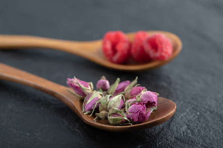 Budding roses and raspberries on wooden spoonsの写真素材