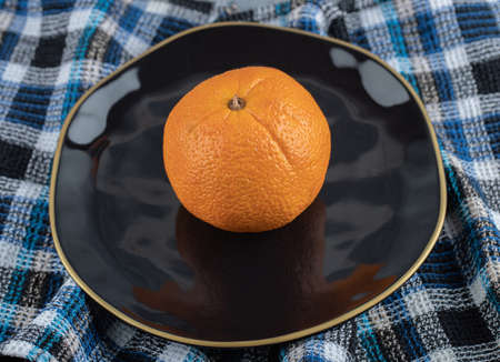 Fresh ripe orange on black plate