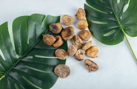 Dried figs with green leaves on white backgroundの写真素材