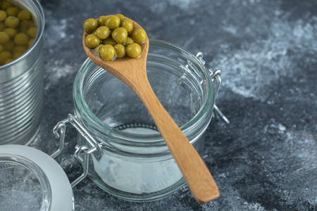 Spoon olive over empty jar on grey backgroundの写真素材