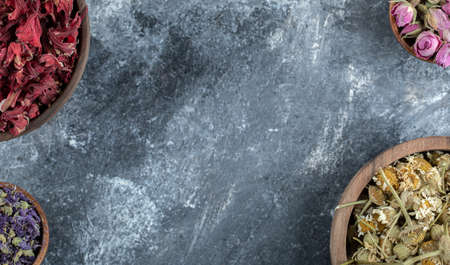 Wooden bowls of dried flowers on marble backgroundの写真素材