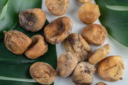 Dried figs with green leaves on white background