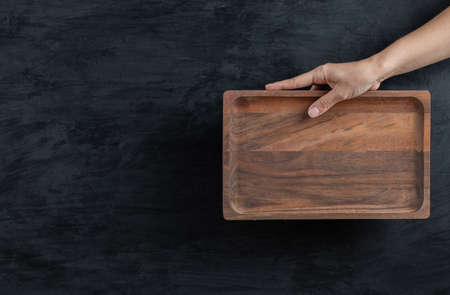 Holding a square wooden board on black backgroundの写真素材