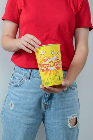 Young girl in red shirt holding a box of popcornsの写真素材