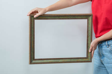 Young girl in red shirt holding a photo frameの写真素材