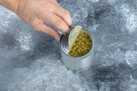 Close up photo of man opening tin olives
