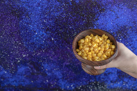Female hand holding Bowl Canned sweet cornsの写真素材