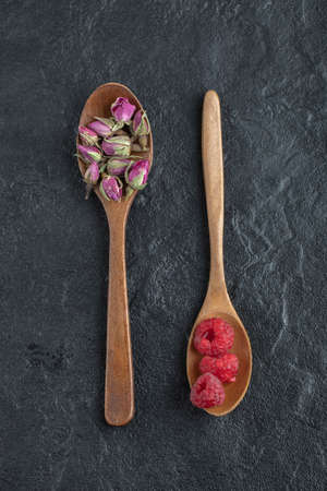 Budding roses and raspberries on wooden spoonsの写真素材