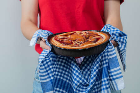 Young girl in red shirt holding a pie in a black pan