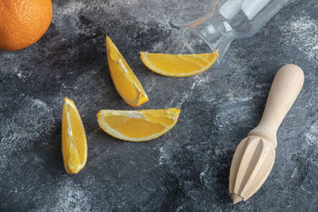 Whole and sliced oranges with empty glass and reamerの写真素材