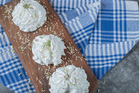 White meringue cookies on a wooden board with coconut powderの写真素材