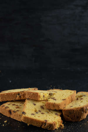 Sliced homemade roulette cake on dark background