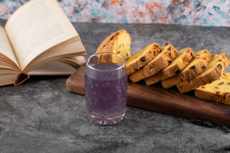 Close up photo of fresh grape cocktail with sliced cake and book