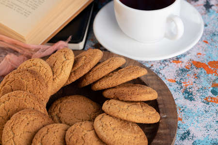 Homemade brown cookies on wooden tray beside of cup of tea