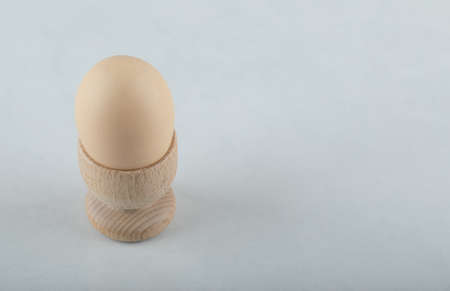 Boiled egg in wooden eggcup on white backgroundの写真素材