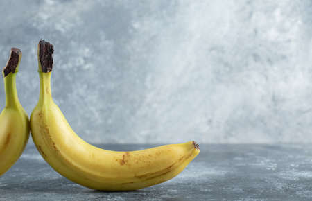 Two ripe bananas over grey background