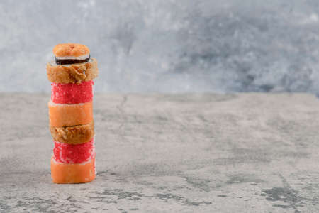 Stack of delicious various sushi rolls on marble background