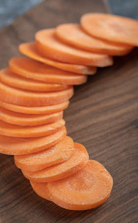 Vertical photo of sliced carrots on wooden board