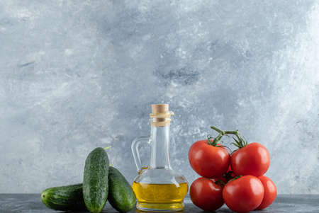 Cucumbers and tomatoes with fresh olive oil on grey backgroundの写真素材