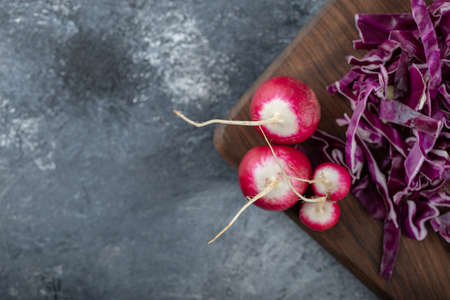Chopped cabbage and radish on wooden board over grey backgroundの写真素材