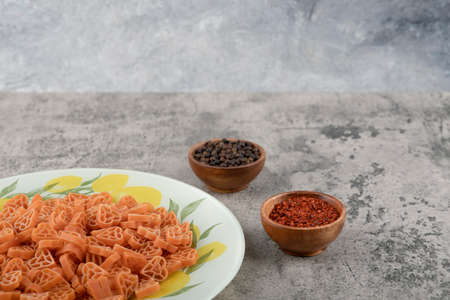 Plate of heart shaped raw macaroni and spices on marble backgroundの写真素材