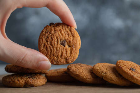 Male hands holding delicious chocolate chip cookies on marble backgroundの写真素材