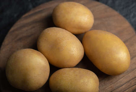 Close up photo of pile of potatoes on wooden cutting boardの写真素材