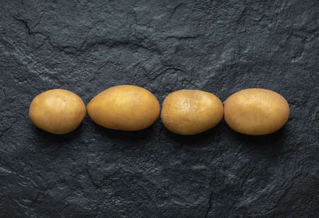 Close up photo of pile of fresh organic potatoes on black backgroundの写真素材