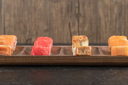 Wooden plate of traditional sushi rolls on black table