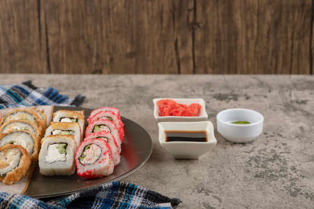Plate of various delicious sushi rolls with soy and wasabi on marble tableの写真素材