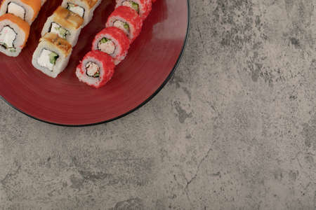 Red plate of various delicious sushi rolls on marble backgroundの写真素材