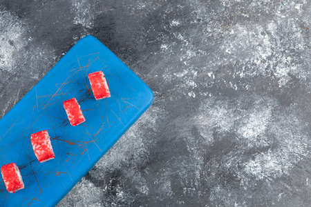 Tasty sushi rolls with red caviar on blue cutting boardの写真素材