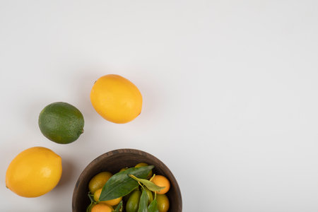 Bowl of fresh kumquats, limes and lemons on white backgroundの写真素材