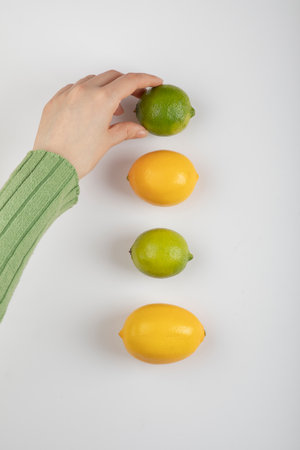 Female hand taking lime out of citric fruits on white backgroundの写真素材