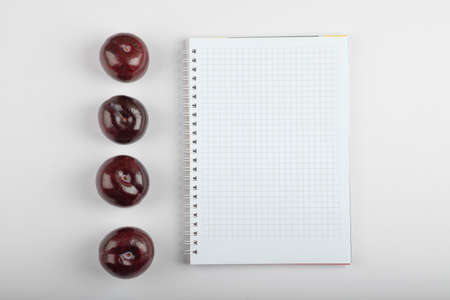 Delicious cherry plums and empty notebook on white backgroundの写真素材