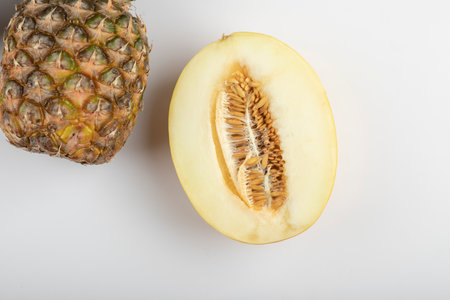 Halved melon and ripe delicious pineapple on white backgroundの写真素材