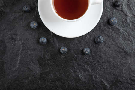 Cup of tea and delicious fresh blueberries on black surfaceの写真素材