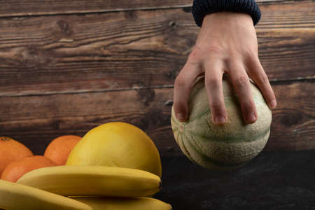 Male hand holding white pumpkin on black tableの写真素材