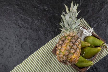 Juicy ripe pineapple and fresh pears in wooden boxの写真素材